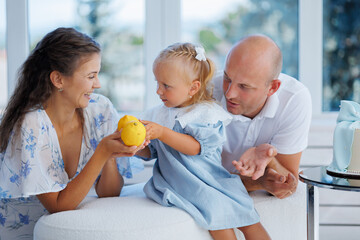 Family engages in playful moment with child indoors near window on a sunny day