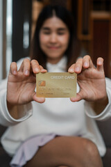 A woman displays a gold credit card, highlighting modern finance and banking concepts with a blurred background.