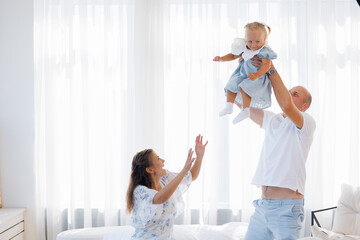 Family enjoys joyful playtime with toddler in bright, airy room during sunny day