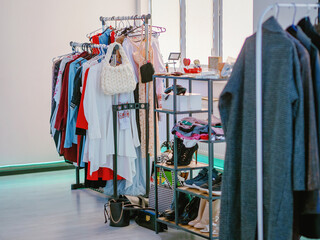 Clothing store with clothes shoes and bags on hanger stands