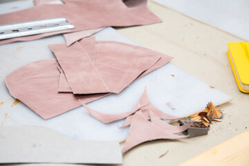 A wooden cutting board that has several pieces of pink leather on its surface