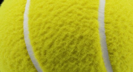 Close-up of a fuzzy yellow tennis ball with two white seams visible, showcasing its textured surface and slight fuzziness