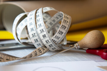 On a table, there lies a measuring tape along with a pair of scissors