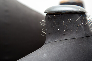 A detailed closeup photograph showcasing a black object adorned with pins
