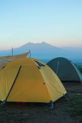 beautiful landscape of a mountain sunrise with a tent at a campground in the morning