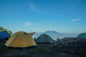 beautiful landscape of a mountain sunrise with a tent at a campground in the morning