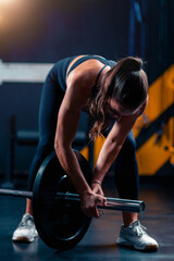 Weight placement on a barbell involves a woman, readying for training to enhance strength in a...