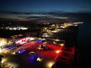 Cityscape at Night: Aerial view of a vibrant city by the ocean at night. The city glows with...