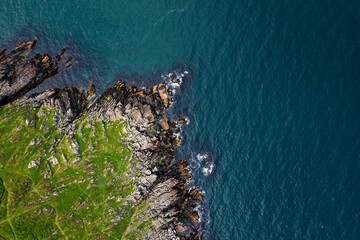 Aerial Top Down View Of Clogherhead Cliffs With Green Pasture Over Rugged Rocks	