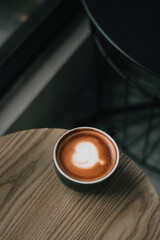 Coffee in black cup on wooden table in coffee shop with lighting background