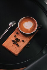 Coffee in black cup on wooden table in coffee shop with lighting background