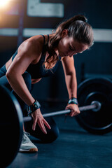 Barbell prep with added weights involves a woman, readying for training to boost strength in a dedicated gym space.