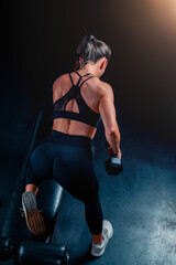 Dumbbell training engages a woman, lifting weights to enhance strength during a productive gym session.