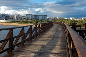 Obraz premium Wooden promenade overlooking stormy bay with boats and dark clouds