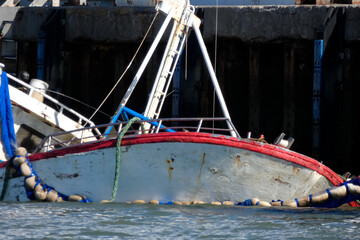 Sunken fishing boat partially submerged in harbor, maritime accident scene