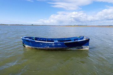 Naklejka premium Small fishing boat beached on sandy shore with debris