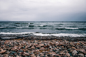 Pebble stone beach of ocean sea pond, summer landscape seascape on cloudy day