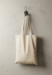 Beige tote bag hanging on hook against textured wall  