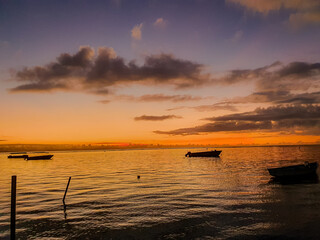 Sonnenuntergang über dem Meer von Mauritius mit beleuchteten Wolken und Booten