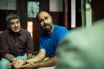 Middle aged men having emotional conversation at therapy session
