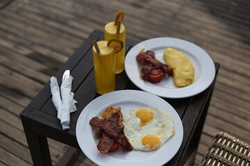Fried Eggs with Bacon and Orange Juice on a Small Wooden Table