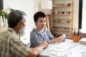 Creative learning. Grandfather and child sorting drawings at home.