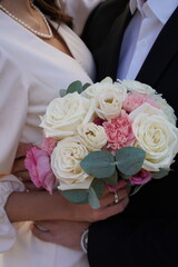 Couple holding a beautiful flower bouquet during their wedding ceremony in an elegant outdoor...