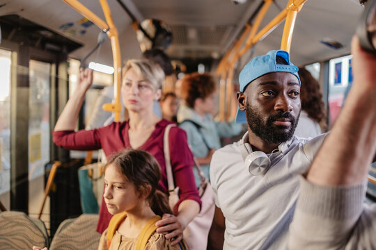 Passengers holding on to handrails while riding public transport bus - Powered by Adobe