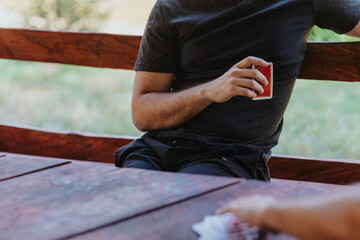 A person holding a deck of playing cards while enjoying an outdoor card game. Relaxed atmosphere...