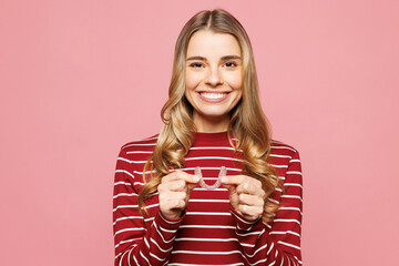 Young smiling cool woman wear red striped sweatshirt casual clothes hold in hand invisible...