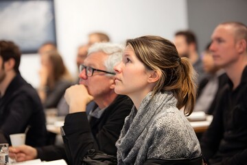 Focused, enthusiastic audience immerses in vibrant, high-tech conference presentation.