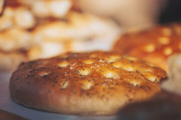 Delicious freshly baked focaccia bread topped with herbs in a warm kitchen setting during the late afternoon