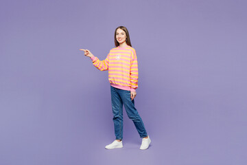 Full body young smiling happy woman she wears yellow sweatshirt casual clothes walk go point finger...