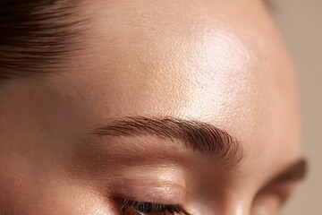 Close-up of smooth forehead illuminated with soft studio lighting.