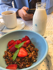 Healthy breakfast with granola, strawberries and milk in modern cafe