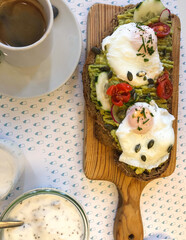 Avocado toast with poached eggs and coffee on outdoor cafe table