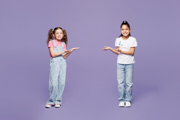 Naklejka premium Full body smiling little two friends kids children girls 9-10 years old wear casual clothes together point hands arms on each other look camera isolated on plain purple background. Lifestyle concept.