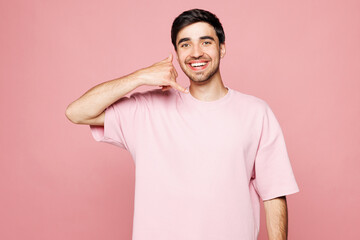 Young smiling happy cool Caucasian man he wearing t-shirt casual clothes doing phone gesture like...