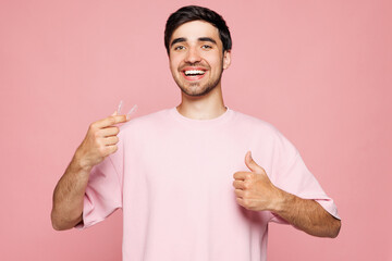Young smiling man wear t-shirt casual clothes hold in hand invisible transparent aligners, silicone...
