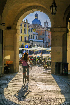 View of cyclist and Piazza delle Erbe through archways and dome of Padua Catherdal visible, Padua, Veneto, Italy