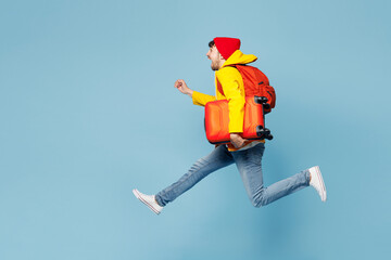 Side view traveler man wear yellow casual clothes jump high run fast hold bag isolated on plain blue background. Tourist travel abroad in free spare time rest getaway. Air flight trip journey concept.