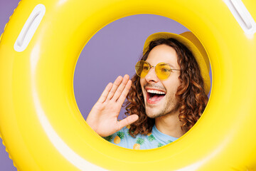 Close up young man in blue beach t-shirt yellow hat sunglasses rest near hotel pool look through...