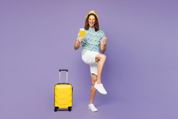 Traveler winner young man hold passport ticket suitcase bag isolated on plain purple background Tourist travel in free time rest getaway. Air flight trip journey, summer vacation sea sun tan concept.
