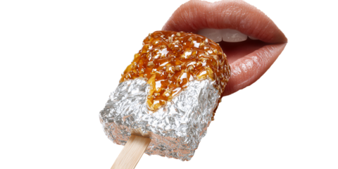 Womans lips biting into a gourmet caramel nut ice cream bar wrapped in foil on a stick Sweet dessert indulgence concept with a delicious treat