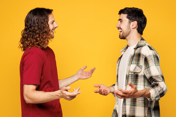 Side profile view young happy two friends buddies men they wear casual clothes together talk speak meet each other isolated on plain yellow orange color background studio portrait. Lifestyle concept.