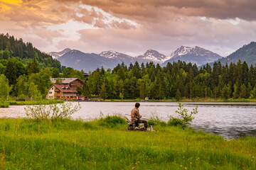 Fisherman and mountainous backdrop at Schwarzsee near Kitzbuhel, Tyrol, Austria