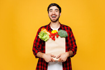 Young shocked surprised man wear casual clothes hold craft paper bag for takeaway mock up with food...
