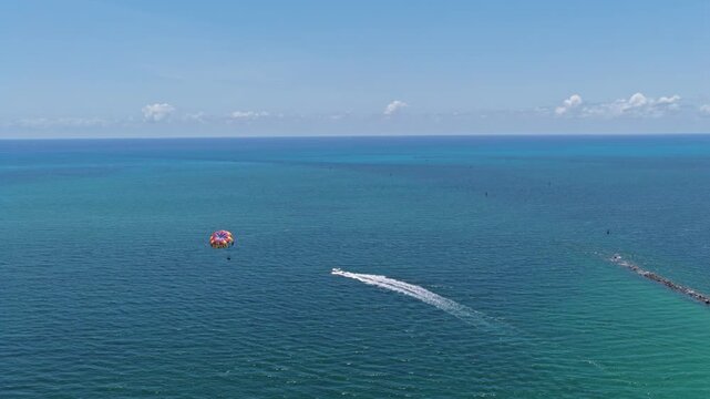 Parasailing sport activity. Parachute in the sky. Extreme rest and parasailing. Summer vacation. Sea sport. Parachute parasail. Water sport on summer vacation. Parasailing recreation with parachute