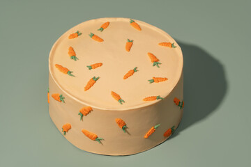 Round bento cake decorated with vibrant carrot designs on a smooth surface, showcasing a delightful...