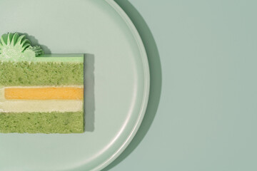 Colorful bento cake slice displayed on a plate, showcasing layers of green pistachio, cream, mango, and passion fruit, highlighting the artistic cross-section of this delightful dessert concept